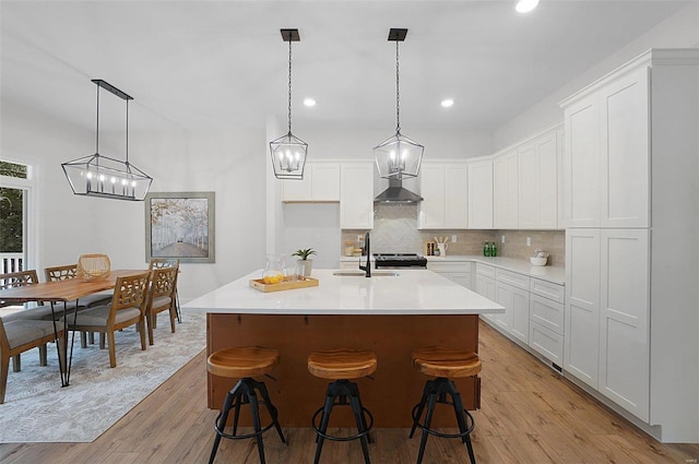 128 Valley Brooke Ct Unit 3Sjm, Washington, MO 63090 - kitchen featuring light wood finished floors, tasteful backsplash, wall chimney range hood, white cabinetry, and recessed lighting