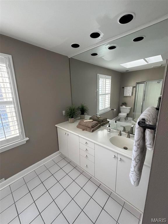 7810 Lafon Pl, University City, MO 63130 - bathroom featuring a skylight, tile patterned flooring, vanity, toilet, and a shower stall