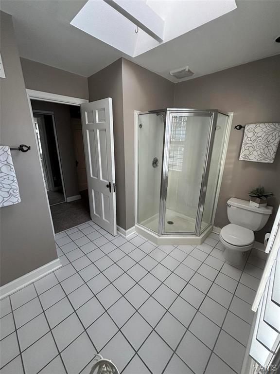 7810 Lafon Pl, University City, MO 63130 - bathroom featuring a skylight, tile patterned flooring, a shower stall, toilet, and baseboards
