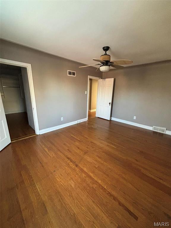 7810 Lafon Pl, University City, MO 63130 - unfurnished bedroom featuring wood finished floors, baseboards, ceiling fan, a walk in closet, and a closet