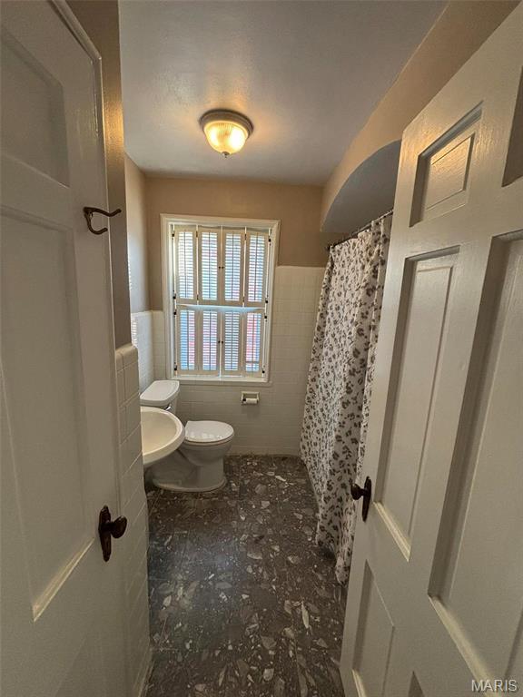 7810 Lafon Pl, University City, MO 63130 - full bathroom with tile walls, toilet, a wainscoted wall, and a shower with shower curtain
