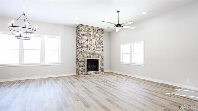 20167 County Road 7300, Newburg, MO 65560 - unfurnished living room with a chandelier, light wood-style flooring, ceiling fan, a stone fireplace, and baseboards