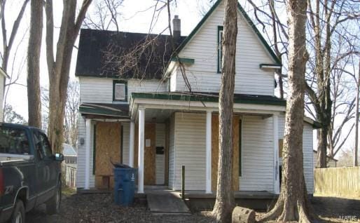 view of front of home with a chimney, a porch, and fence