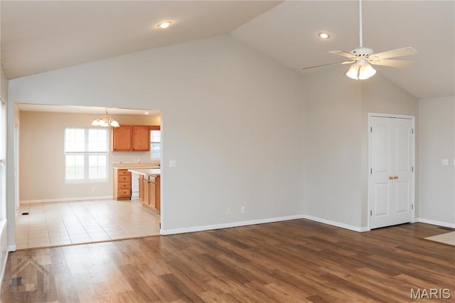 20981 Lacombe Rd, Waynesville, MO 65583 - unfurnished living room featuring a chandelier, a ceiling fan, high vaulted ceiling, wood finished floors, and baseboards