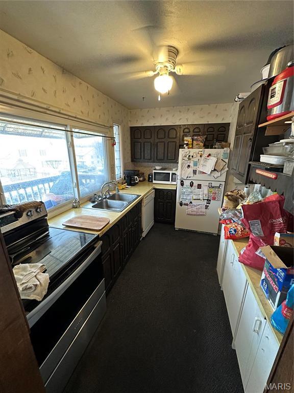 4290 Chateau De Ville Dr Unit G, Saint Louis, MO 63129 - kitchen featuring appliances with stainless steel finishes, a sink, wallpapered walls, light countertops, and dark carpet