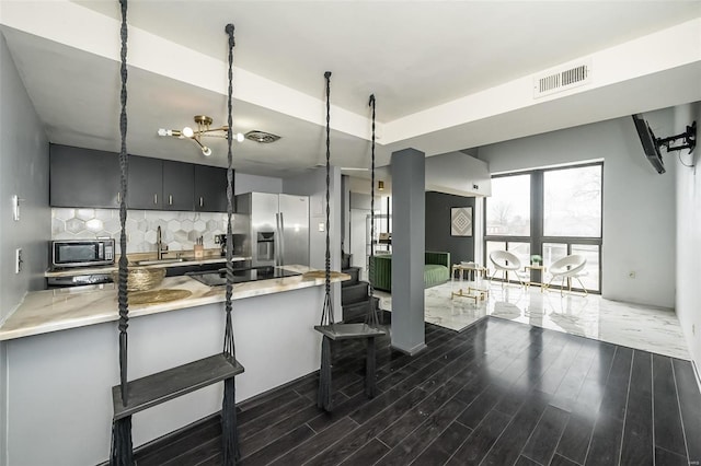 1523 S 10th St Unit 207, Saint Louis, MO 63101 - kitchen with appliances with stainless steel finishes, backsplash, dark wood finished floors, a breakfast bar, and a peninsula