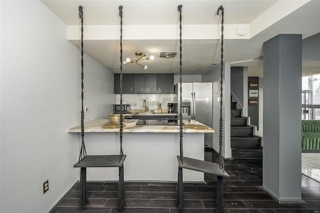 1523 S 10th St Unit 207, Saint Louis, MO 63101 - kitchen featuring a peninsula, backsplash, light countertops, a breakfast bar area, and stainless steel refrigerator with ice dispenser