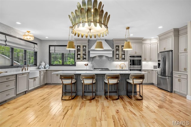 130 Foristell Ridge Ct, Foristell, MO 63348 - kitchen featuring appliances with stainless steel finishes, gray cabinets, custom exhaust hood, a kitchen island, and backsplash