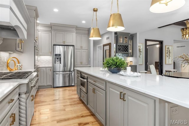 130 Foristell Ridge Ct, Foristell, MO 63348 - kitchen with appliances with stainless steel finishes, gray cabinets, backsplash, light wood-type flooring, and custom exhaust hood