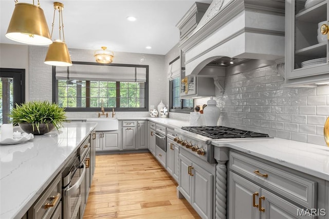 130 Foristell Ridge Ct, Foristell, MO 63348 - kitchen with gray cabinetry, stainless steel gas stovetop, premium range hood, light wood-style floors, and tasteful backsplash