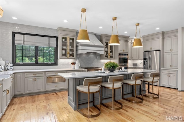 130 Foristell Ridge Ct, Foristell, MO 63348 - kitchen featuring gray cabinetry, premium range hood, stainless steel appliances, a warming drawer, and a center island