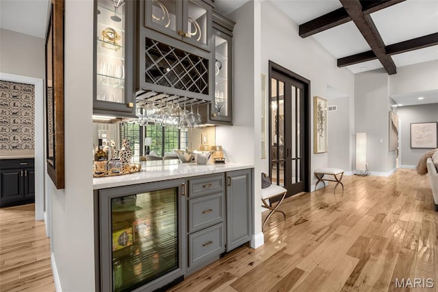 130 Foristell Ridge Ct, Foristell, MO 63348 - indoor wet bar featuring beverage cooler, beamed ceiling, light wood-type flooring, and coffered ceiling
