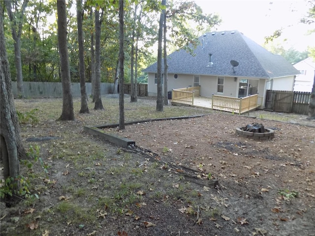 1002 Cypress Dr, Rolla, MO 65401 - back of property featuring a fire pit, a wooden deck, a fenced backyard, and roof with shingles