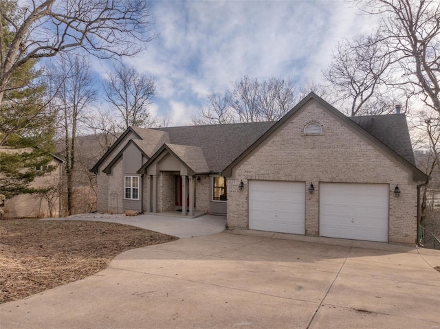 view of front of house with concrete driveway, brick siding, a garage, and roof with shingles