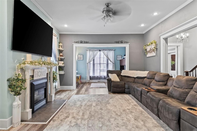 821 N State St, Litchfield, IL 62056 - living room with wood finished floors, a tiled fireplace, ceiling fan, crown molding, and a chandelier