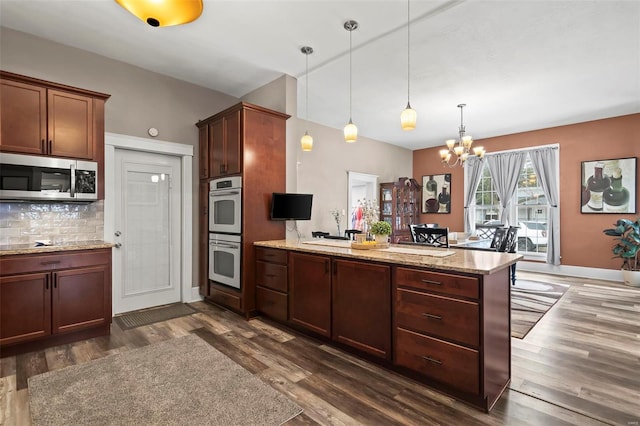 821 N State St, Litchfield, IL 62056 - kitchen featuring stainless steel appliances, a peninsula, a chandelier, dark wood-type flooring, and tasteful backsplash