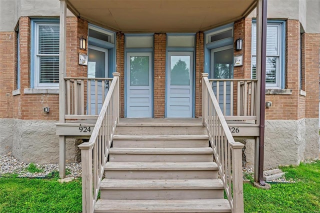 doorway to property with brick siding and a porch