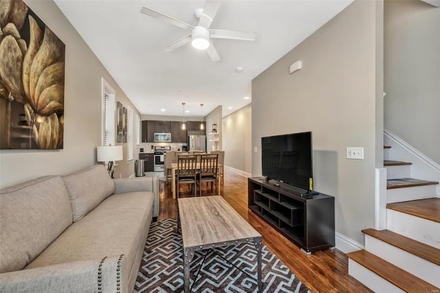 living area with dark wood finished floors, stairway, ceiling fan, and baseboards