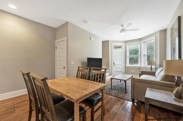 dining space featuring a ceiling fan, dark wood finished floors, and baseboards