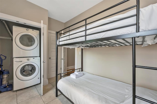 bedroom with stacked washer / dryer and light tile patterned floors