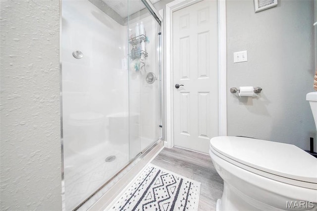 12455 Jefferys Pl, Rolla, MO 65401 - bathroom featuring a textured wall, toilet, a stall shower, and wood finished floors
