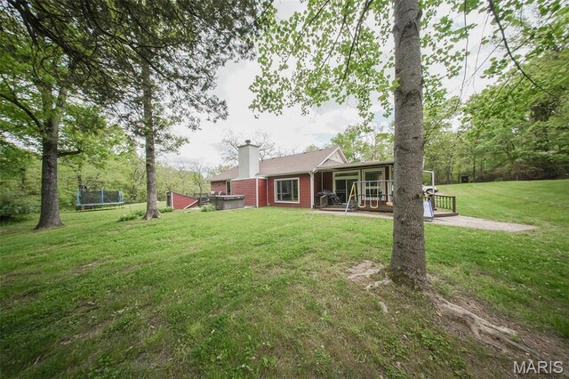 12455 Jefferys Pl, Rolla, MO 65401 - rear view of property with a trampoline, a sunroom, a lawn, a hot tub, and a chimney
