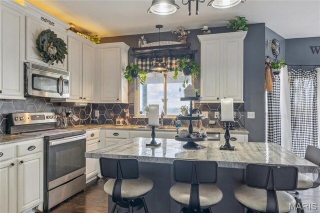 8038 Fox Holw, Barnhart, MO 63012 - kitchen with stainless steel appliances, white cabinets, a breakfast bar area, and tasteful backsplash