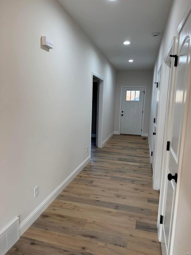 hallway featuring baseboards, wood finished floors, and recessed lighting