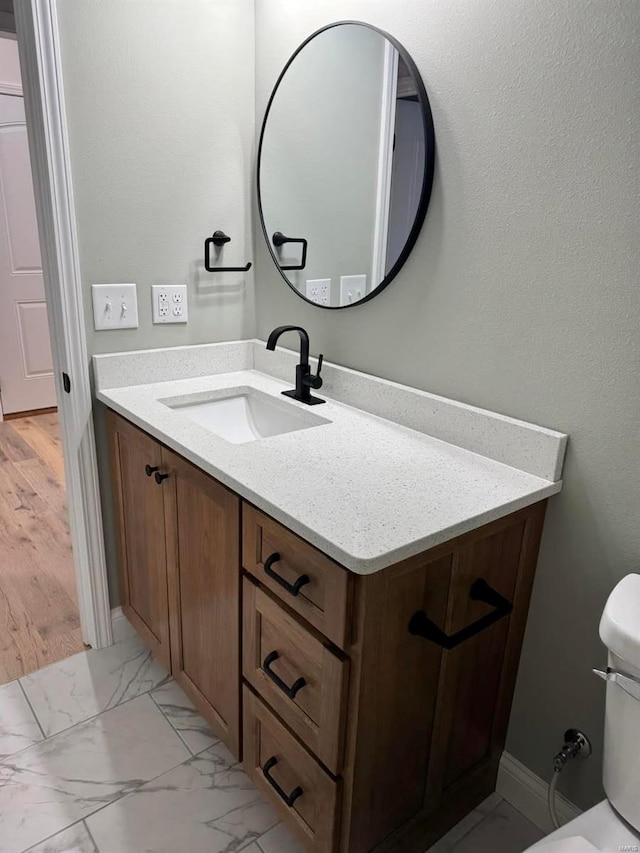 bathroom with vanity, toilet, and marble finish flooring