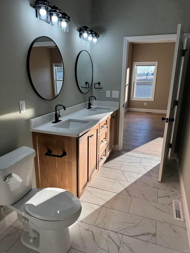 bathroom with marble look tiles, baseboards, toilet, and double vanity