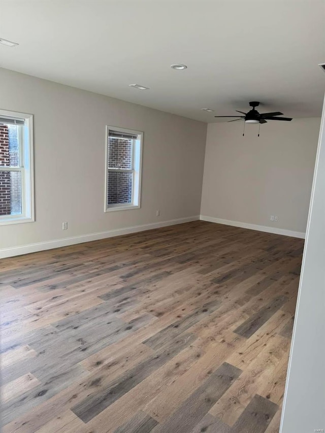 empty room with baseboards, wood finished floors, ceiling fan, and recessed lighting