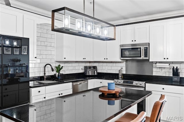 kitchen with stainless steel appliances, a sink, ornamental molding, white cabinetry, and tasteful backsplash
