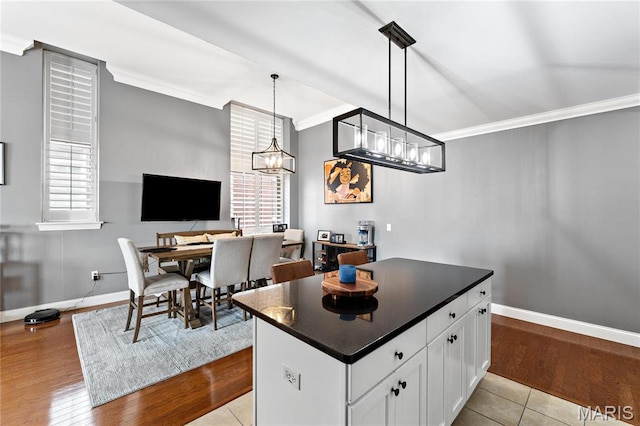kitchen featuring crown molding, dark countertops, white cabinets, baseboards, and healthy amount of natural light