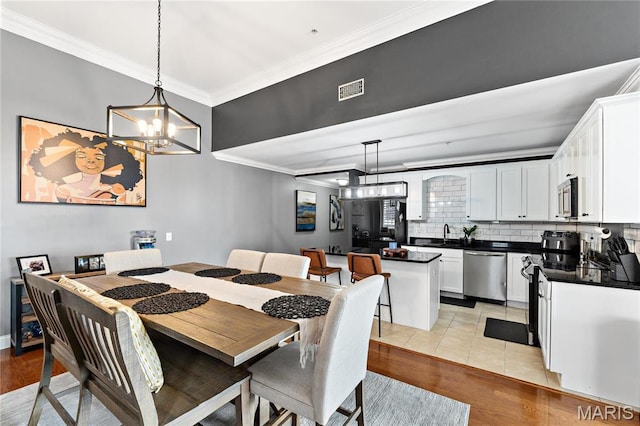 dining area featuring crown molding, a chandelier, and light wood finished floors
