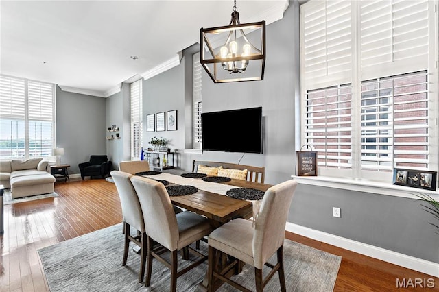 dining area featuring ornamental molding, a chandelier, wood finished floors, and baseboards