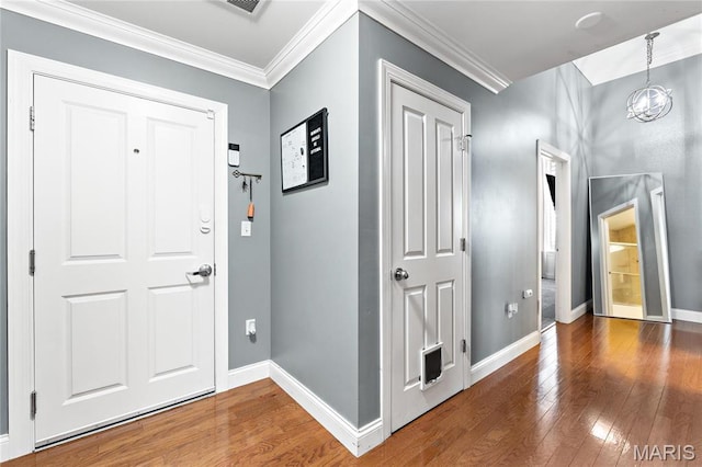entryway featuring wood-type flooring, a chandelier, baseboards, and crown molding