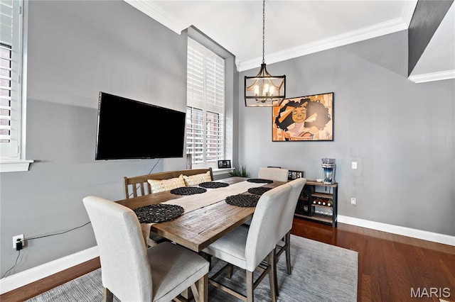 dining room with a chandelier, ornamental molding, wood finished floors, and baseboards