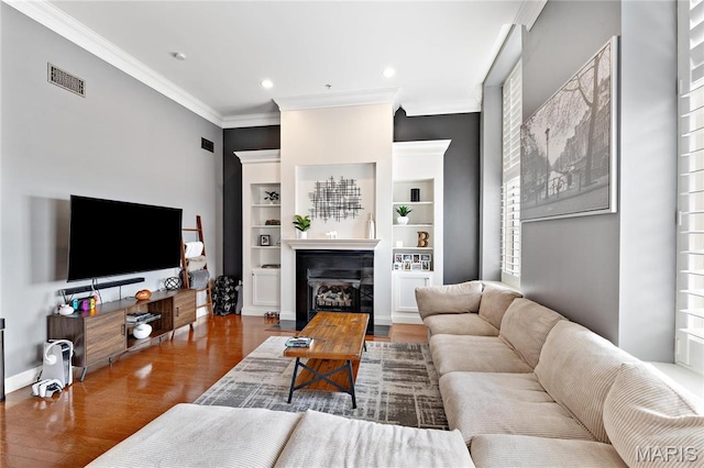 living room featuring wood finished floors, crown molding, a glass covered fireplace, recessed lighting, and baseboards