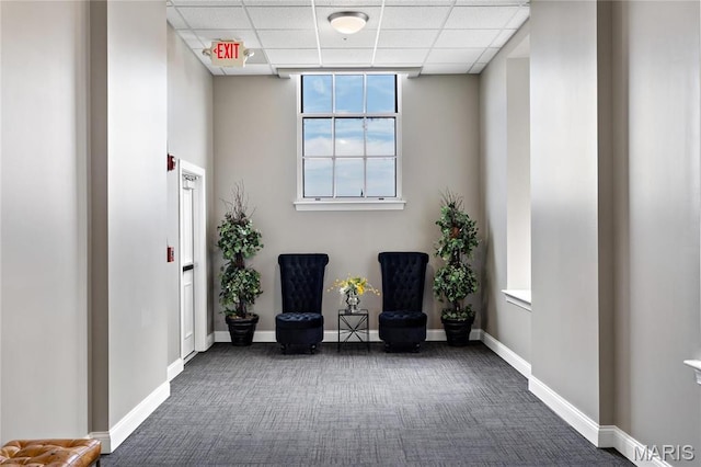 sitting room featuring carpet, a paneled ceiling, and baseboards