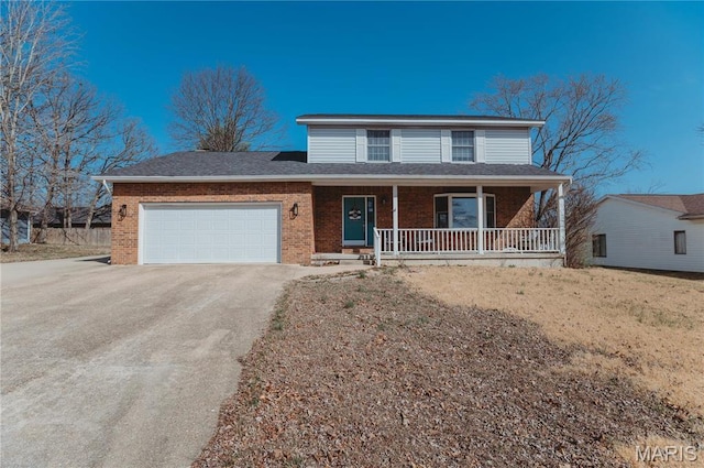 traditional-style home with driveway, covered porch, brick siding, and a garage