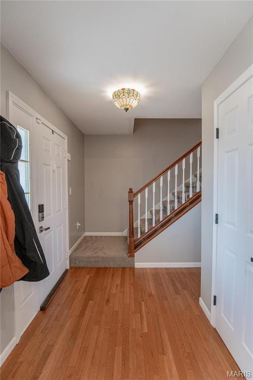 entryway with light wood-style floors, stairs, and baseboards