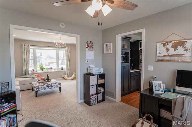 home office with a chandelier, ceiling fan, light carpet, and baseboards