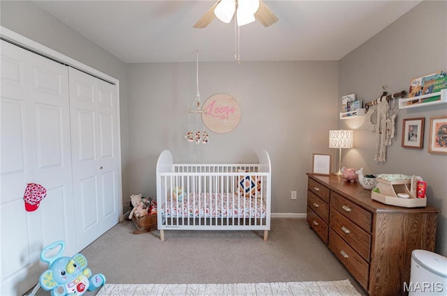 bedroom featuring a closet, a nursery area, light colored carpet, a ceiling fan, and baseboards