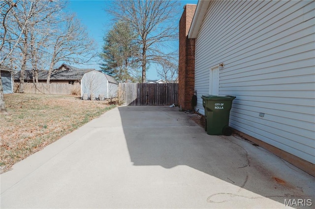 view of patio featuring a storage shed, fence, and an outbuilding