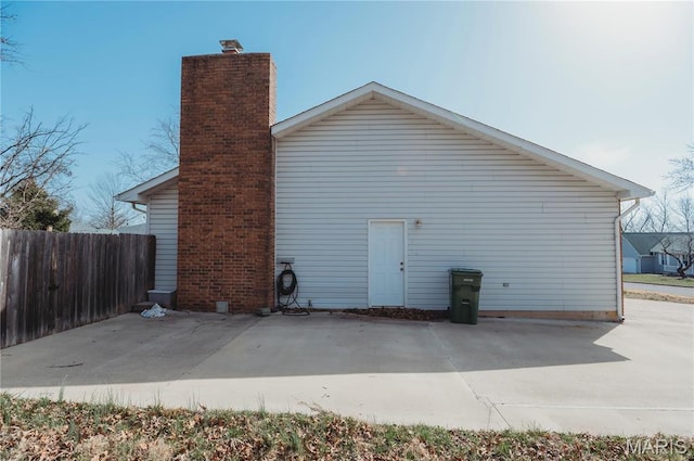 rear view of house featuring fence, a chimney, and a patio area