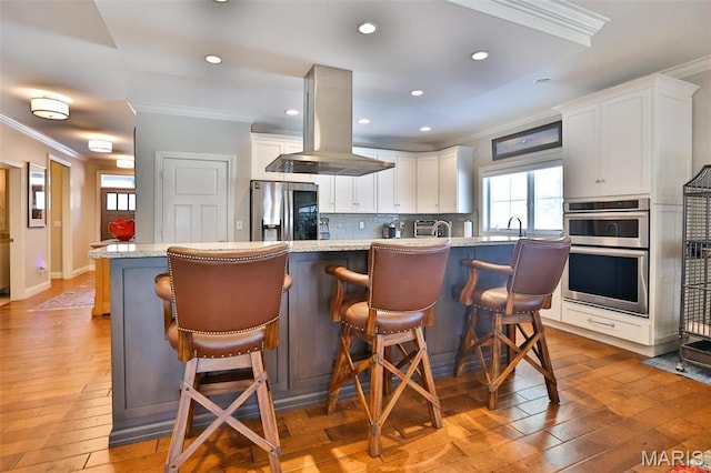 1120 Franklin Ave, Edwardsville, IL 62025 - kitchen with appliances with stainless steel finishes, crown molding, island range hood, light wood-type flooring, and tasteful backsplash