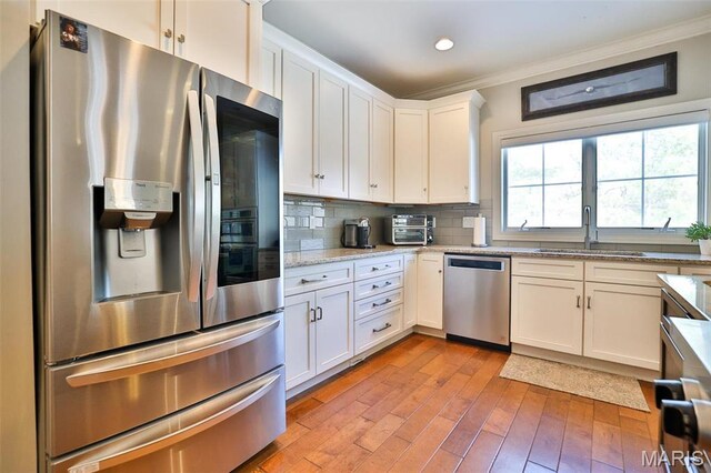 1120 Franklin Ave, Edwardsville, IL 62025 - kitchen with appliances with stainless steel finishes, crown molding, light wood-style floors, white cabinetry, and decorative backsplash