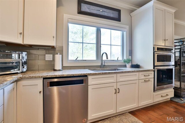 1120 Franklin Ave, Edwardsville, IL 62025 - kitchen with stainless steel appliances, ornamental molding, dark wood-style floors, white cabinetry, and tasteful backsplash