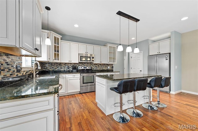615 Derby Way Dr, Wentzville, MO 63385 - kitchen featuring stainless steel appliances, decorative backsplash, a breakfast bar area, a center island, and light wood-style flooring