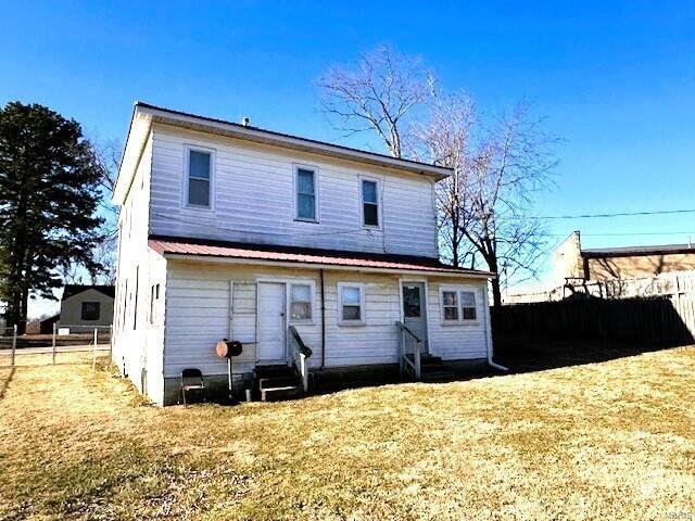 rear view of house featuring entry steps, a fenced backyard, and metal roof